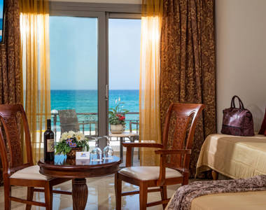 Ariadne Hotel Malia Luxury Studio indoor table with a bottle of wine and glasses, two chairs and amenities