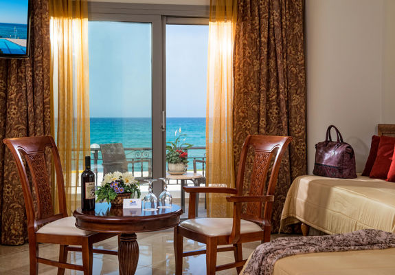 Ariadne Hotel Malia Luxury Studio indoor table with a bottle of wine and glasses, two chairs and amenities