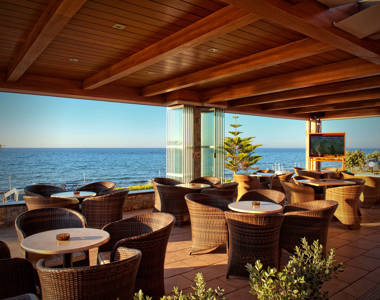 Ariadne Hotel Malia bar sitting area with round tables and armchairs and sea view